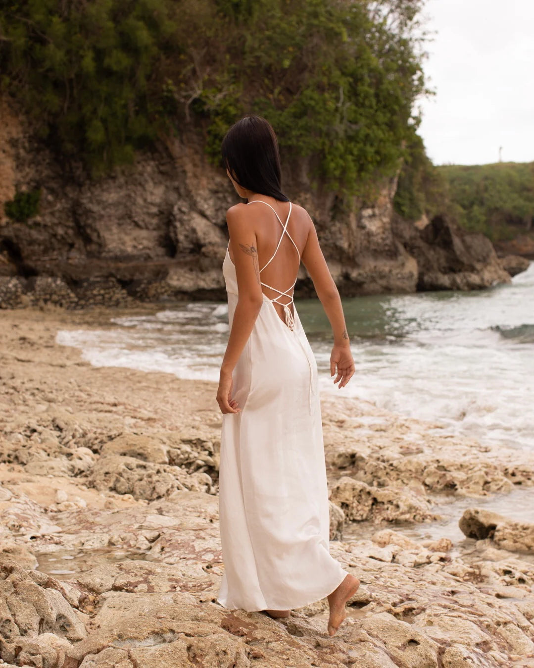 Model in white silk maxi dress on Bingin Beach